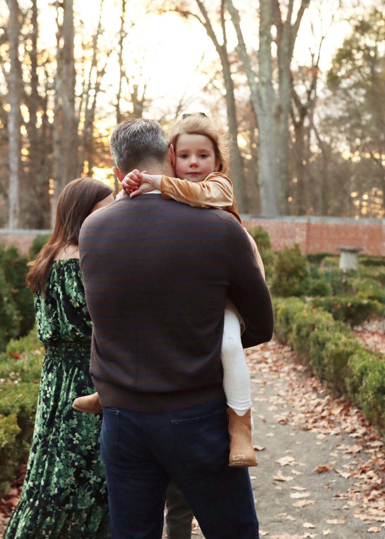 Evan carrying his daughter through a garden at sunset